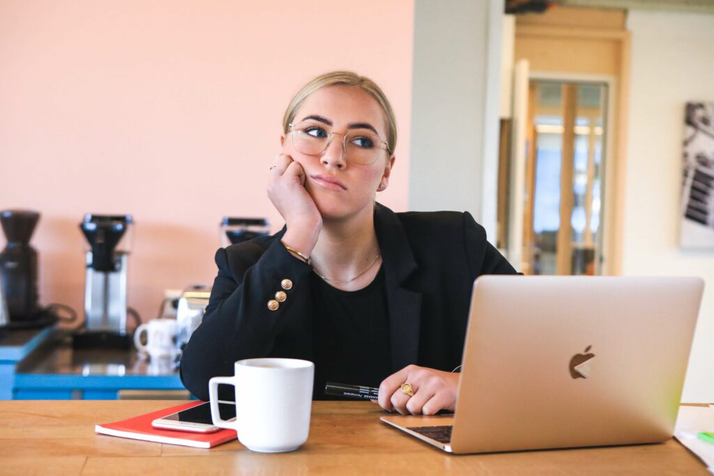 Woman at a desk, thinking about whether she should use tror synes or mener in Danish.