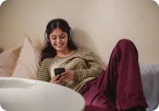 A learner relaxing on a sofa, smiling at her progress on her phone
